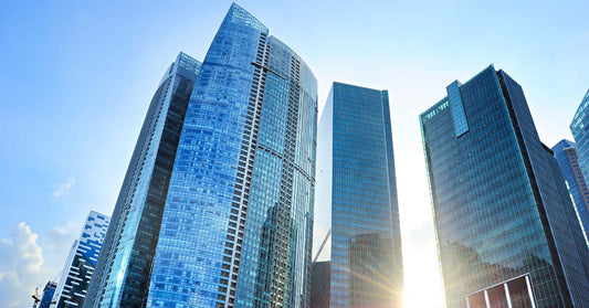 Tall glass skyscrapers in Singapore reflecting sunlight against a clear blue sky.