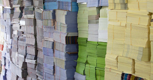 Stacks of various colored NCR bill books ready for printing in Singapore.