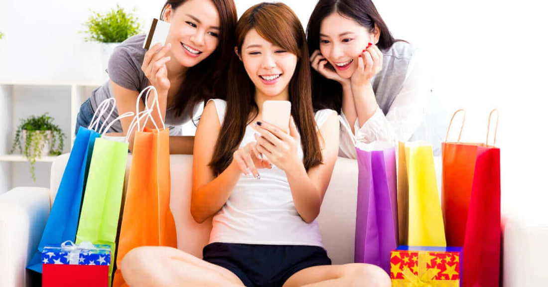 Three happy young women enjoying shopping, surrounded by colorful paper bags, celebrating their purchases together.