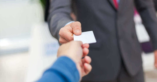 Businessman handing a blank business card to another person, highlighting networking and professional exchanges.