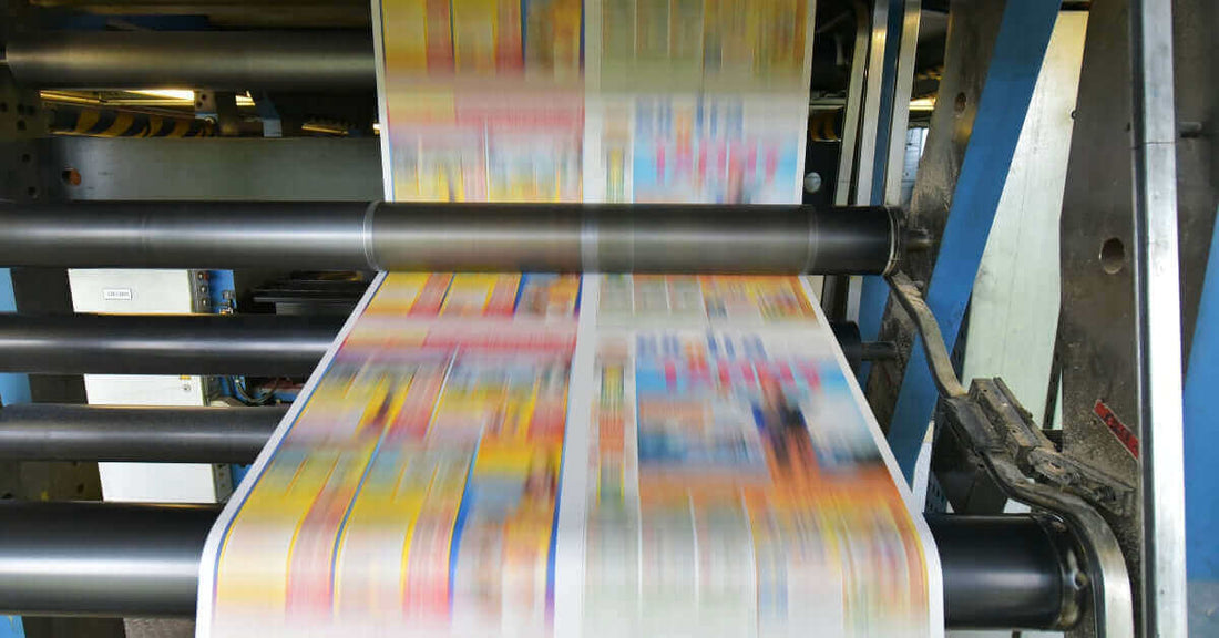 Close-up of a printing press with colorful flyers in motion, showcasing traditional printing in a digital era.